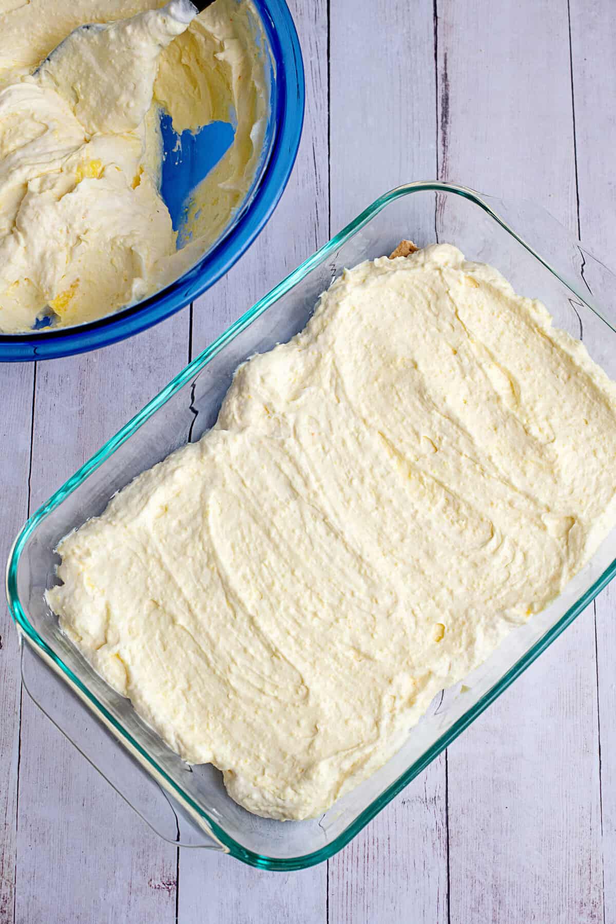 Spreading a layer of vanilla pudding mix over the graham cracker base