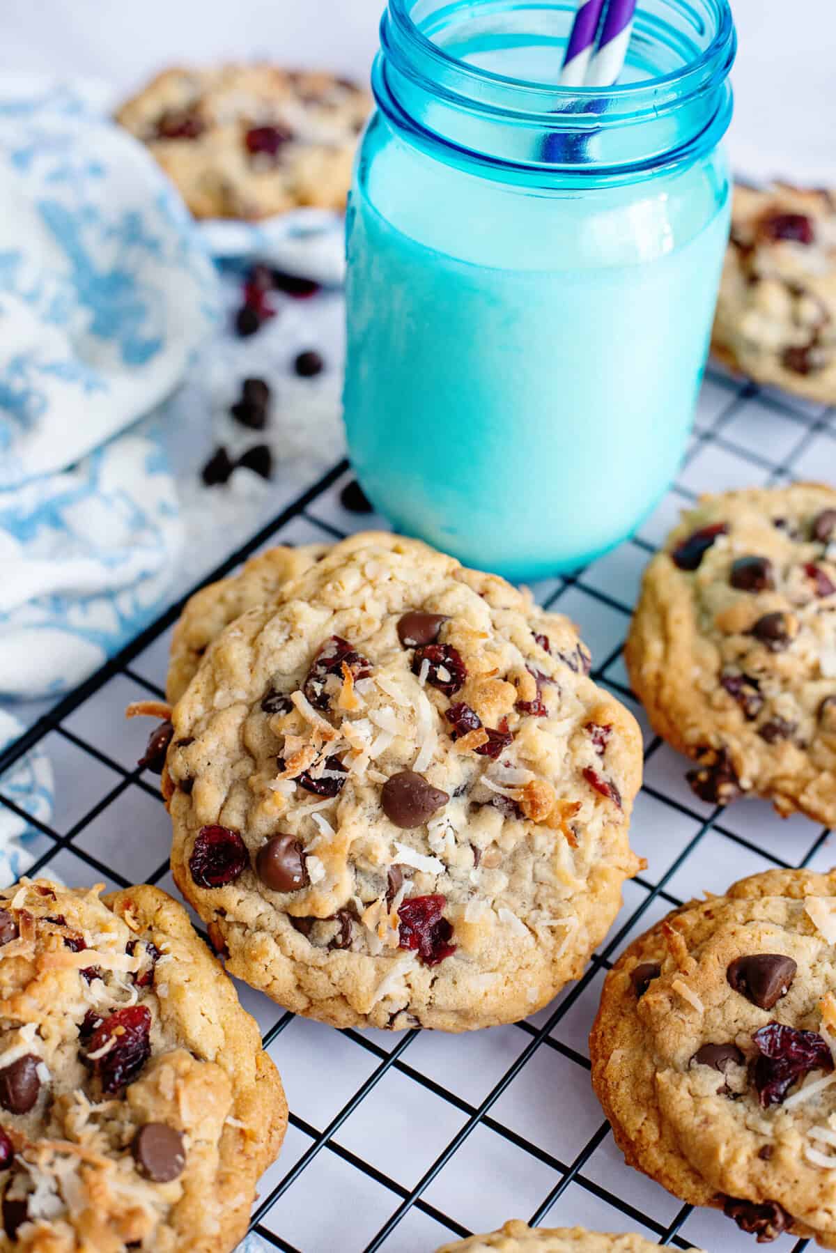 Baked chocolate chip cookies on a wire rack next to a glass of milk