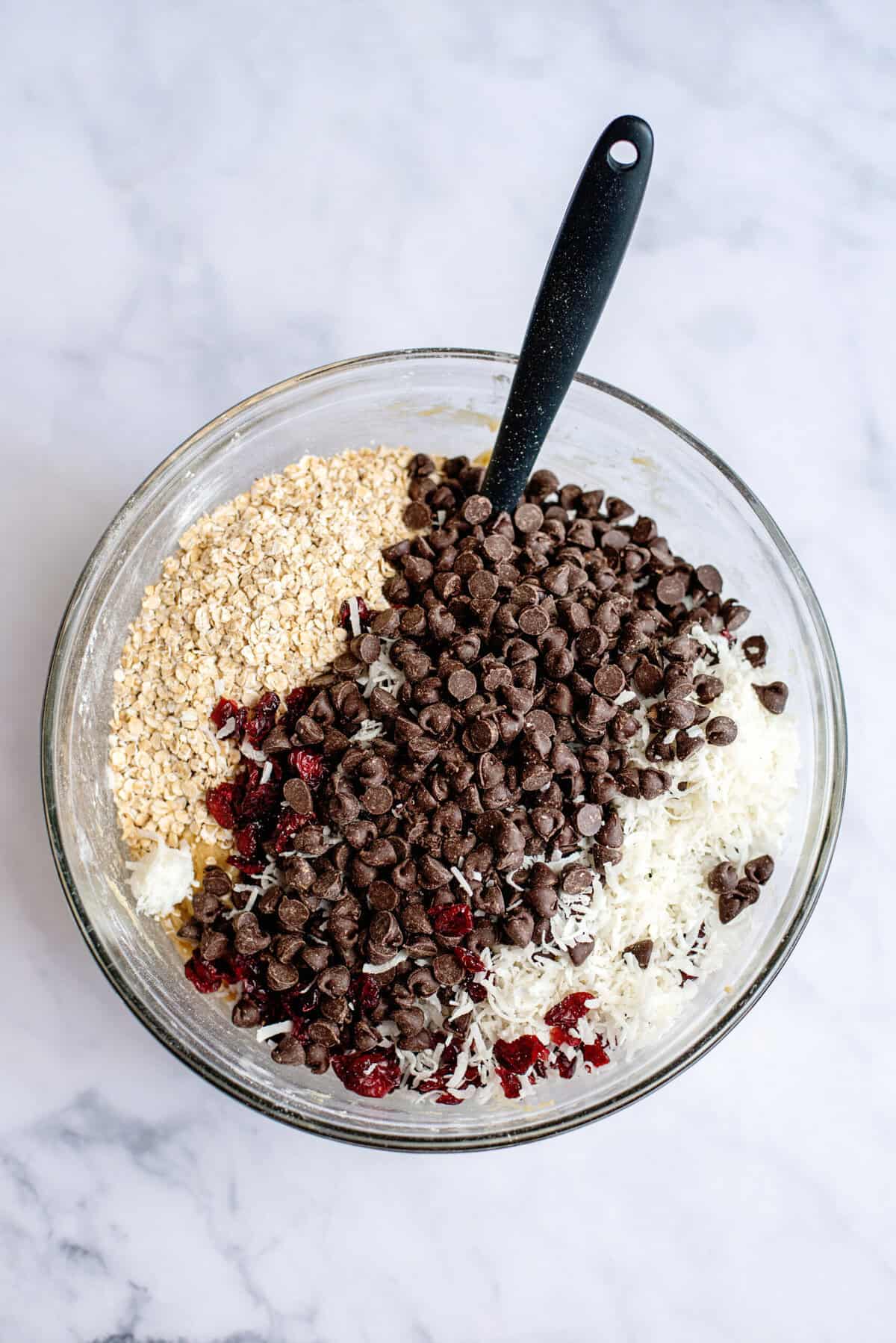 Adding chocolate chips and berries to the bowl of mixed ingredients