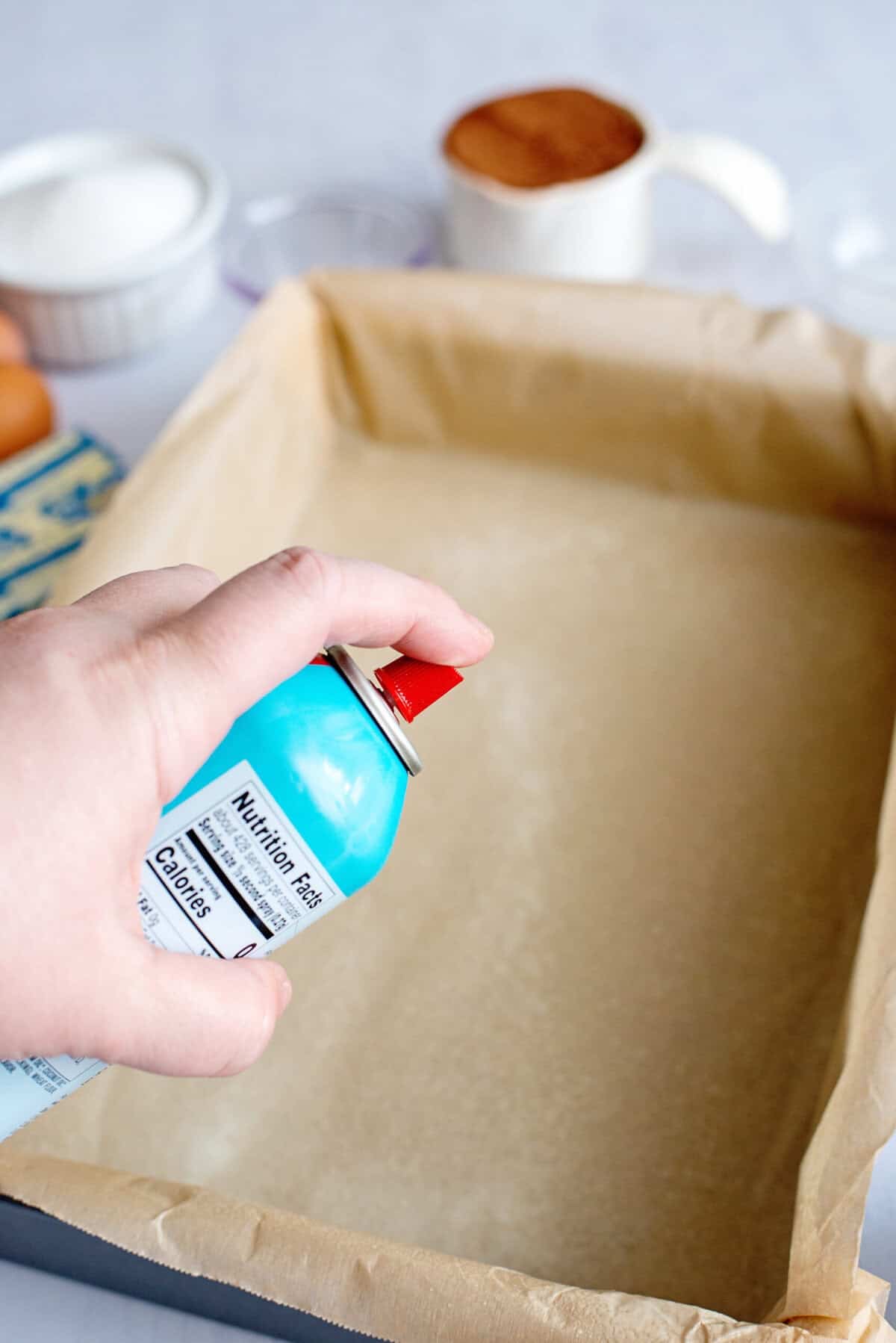 Spraying a parchment-paper-lined baking pan with non-stick spray