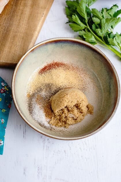A bowl with brown sugar, smoked paprika, garlic, onion powder, black pepper, salt, and cayenne