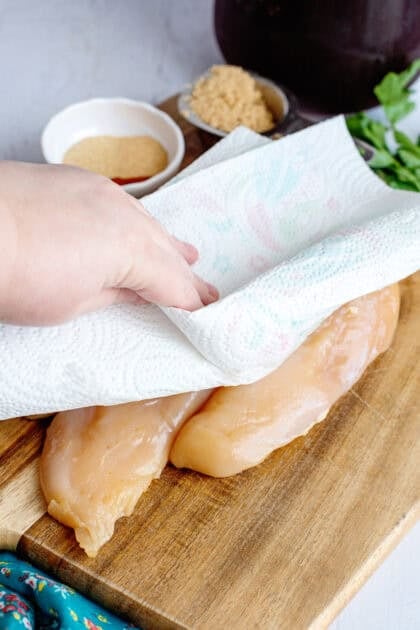 Drying the soaked raw chicken with a paper towel