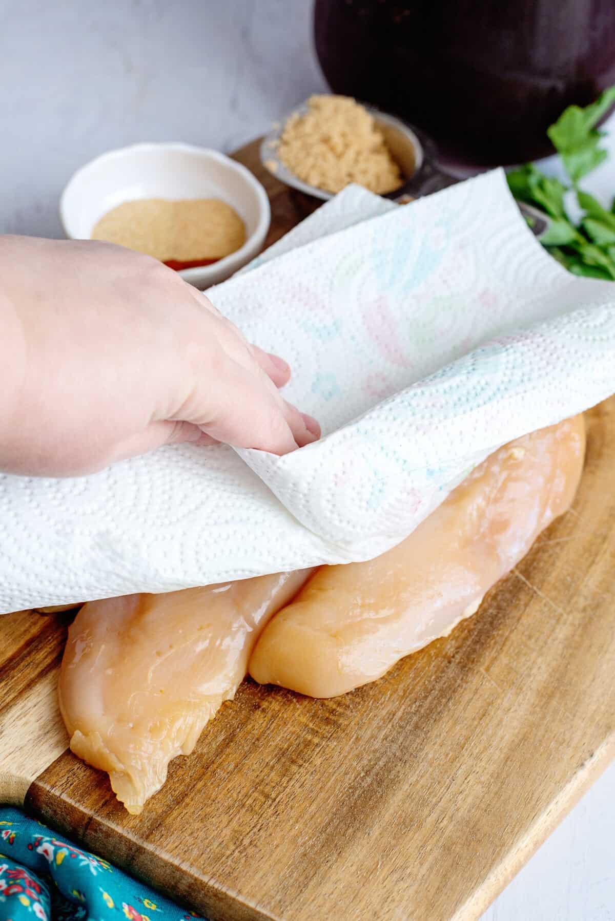 Drying the soaked raw chicken with a paper towel