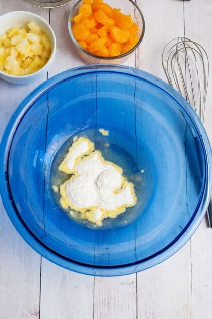 Adding the instant dry pudding mix into the fruit juices in a mixing bowl