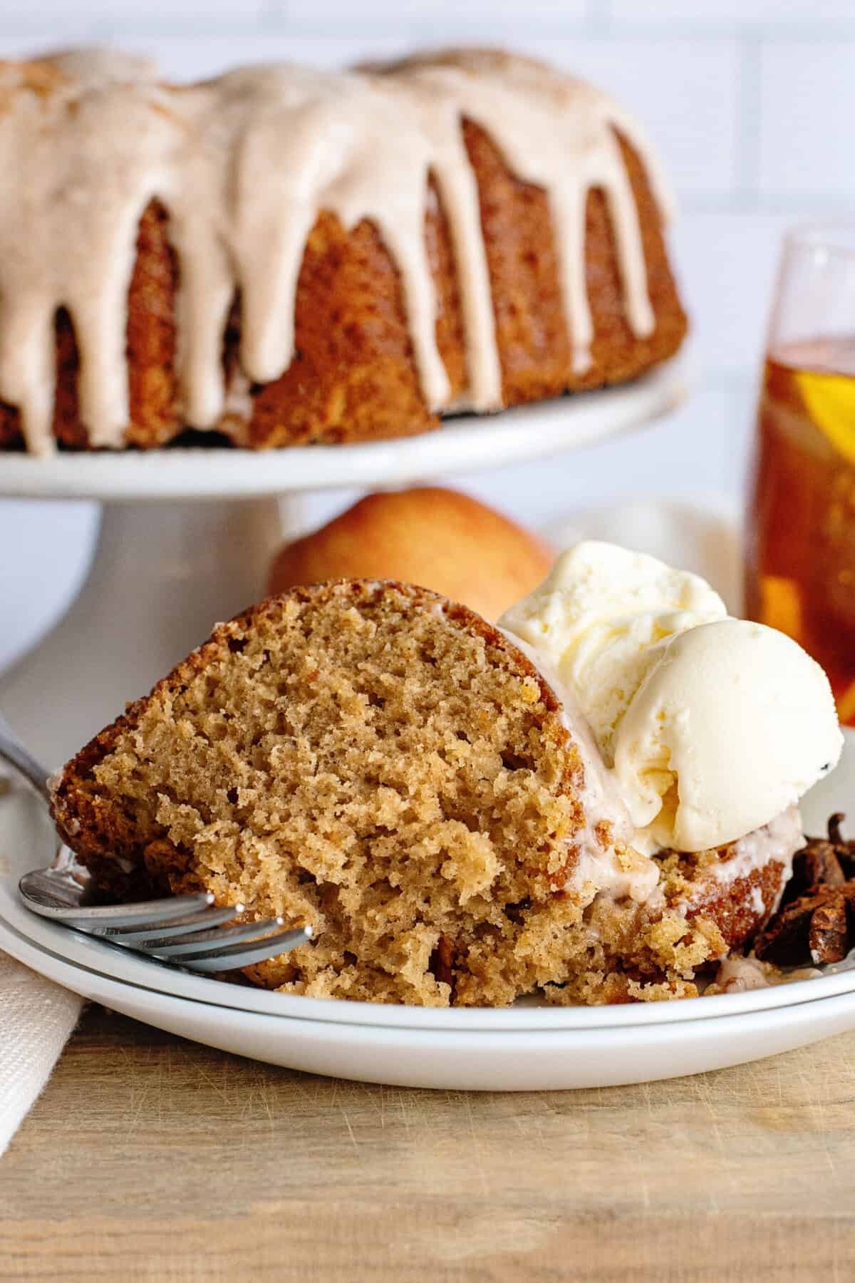 A plate of apple cider bundt cake on a white plate with a side of vanilla ice cream.