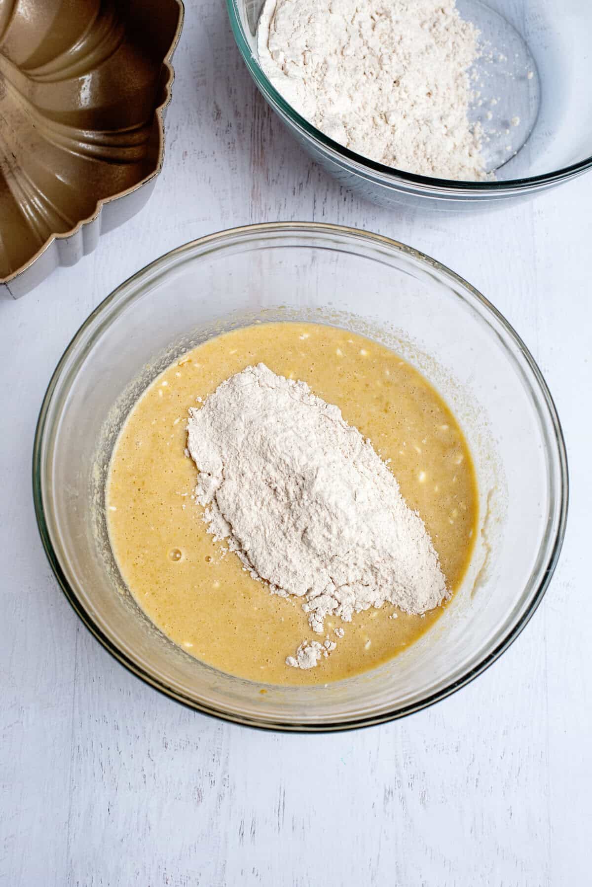 Combining the wet and dry ingredients in a glass mixing bowl.