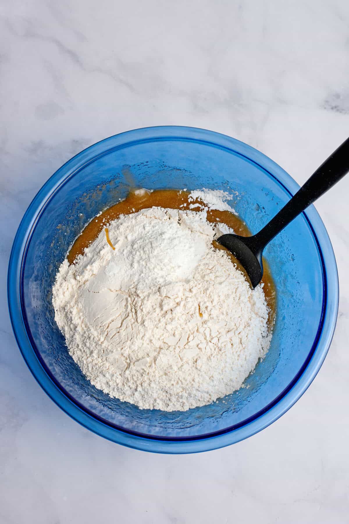 Adding dry ingredients to a mixing bowl.
