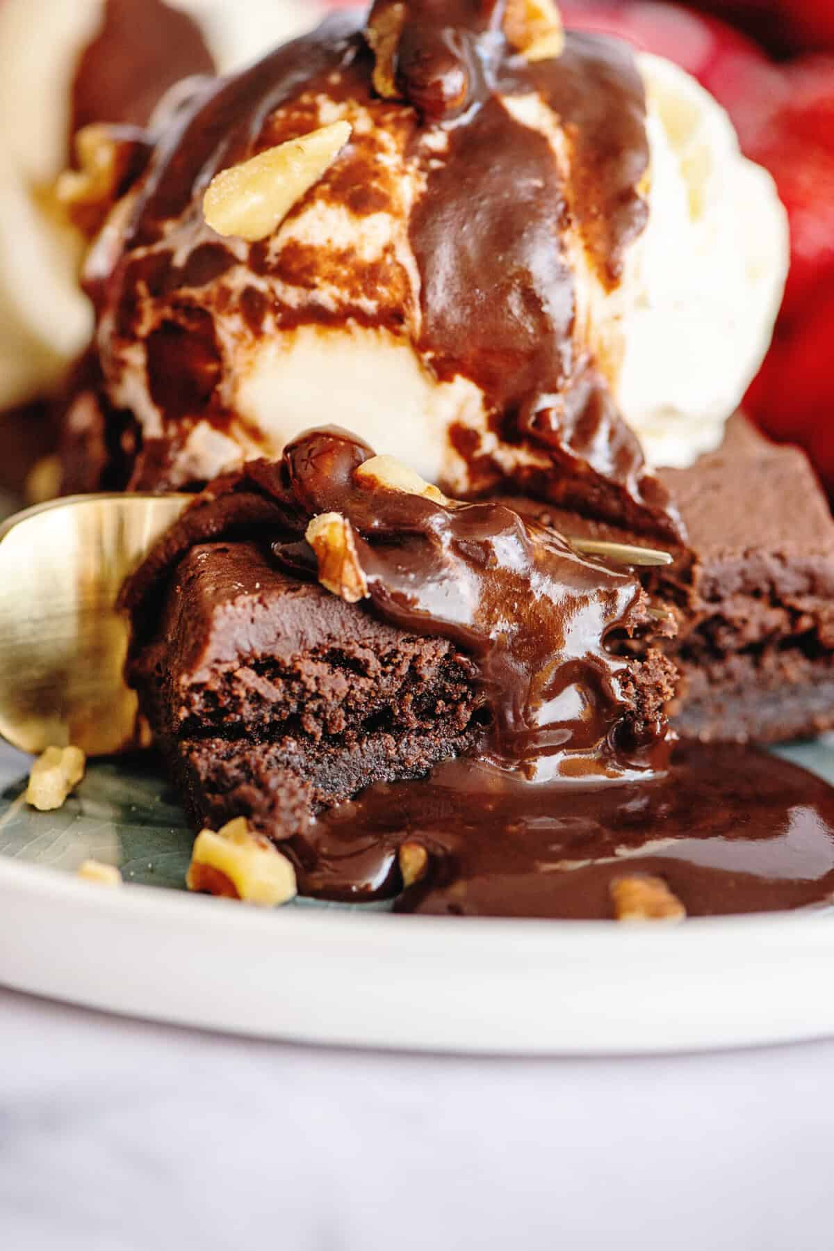 Hot fudge drizzling down a plate of ice cream and brownies.