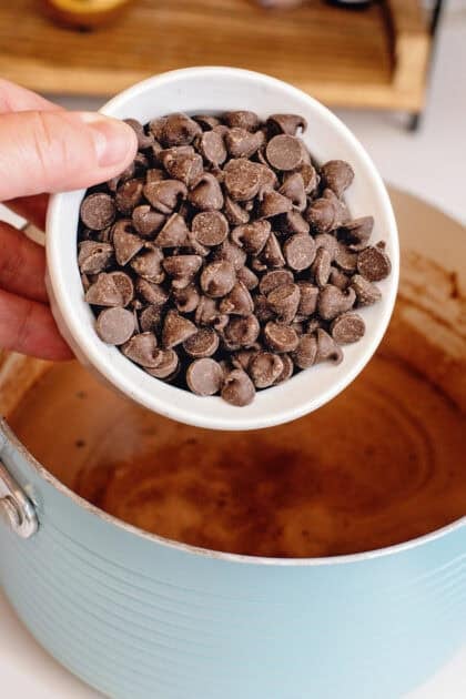 Adding chocolate chips to a saucepan.