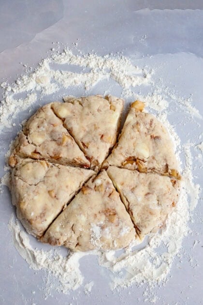 A flat circle of scone dough cut into wedges.