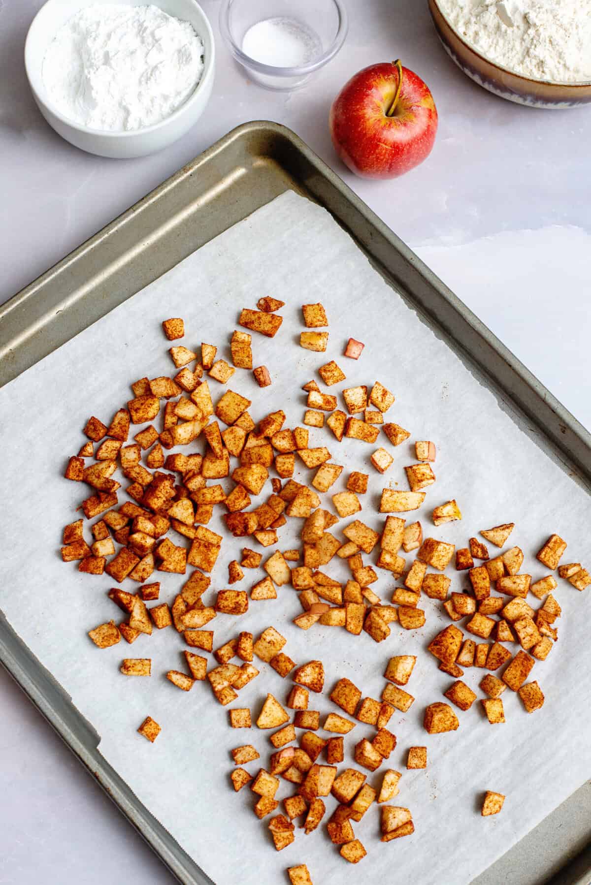 Diced baked apples in a baking sheet.