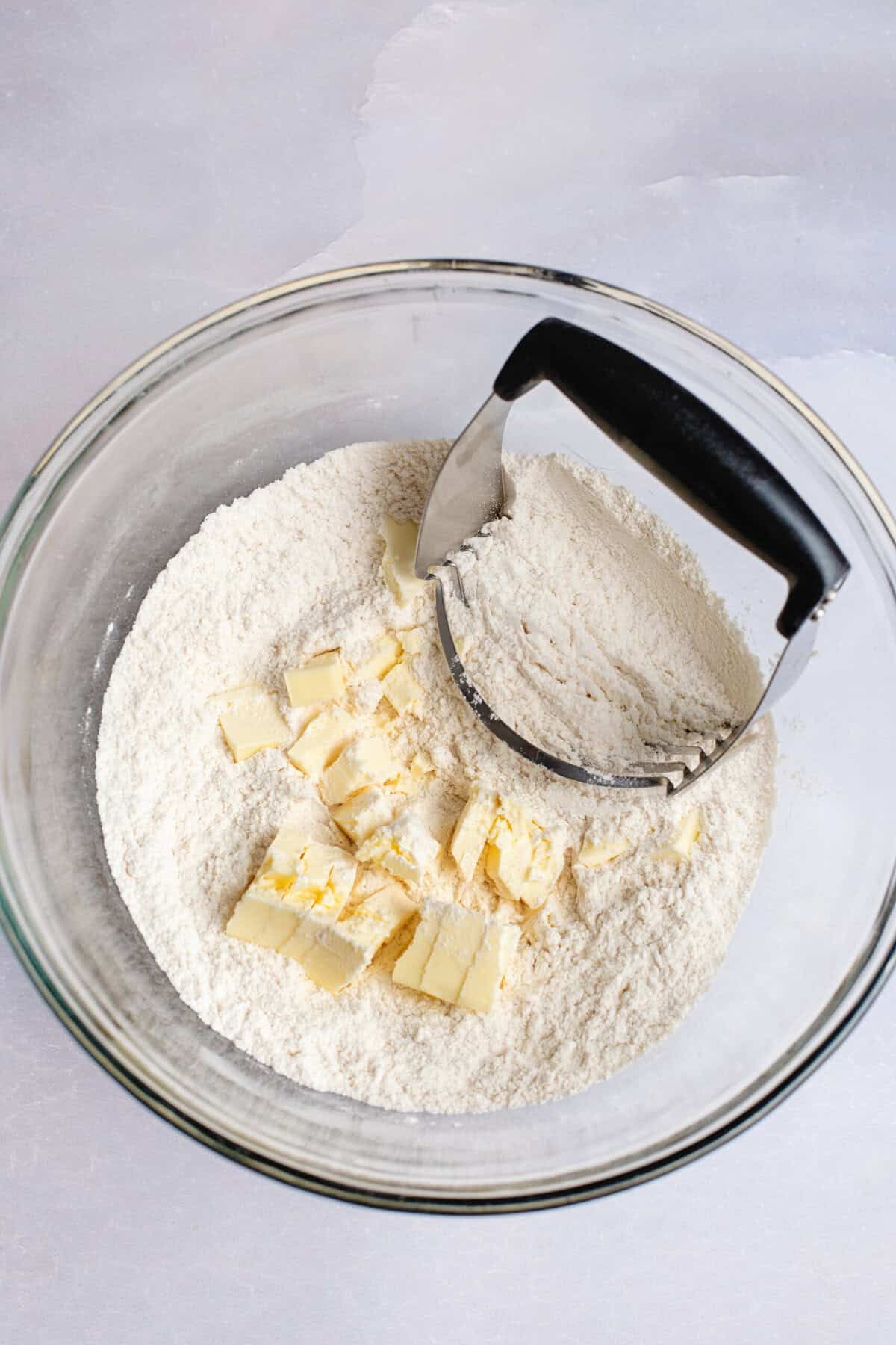 Cutting the butter into dry ingredients in a glass mixing bowl.
