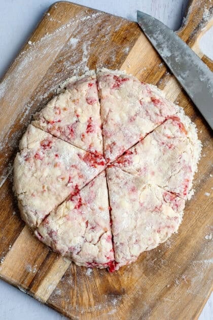Raspberry scone dough sliced into wedges.