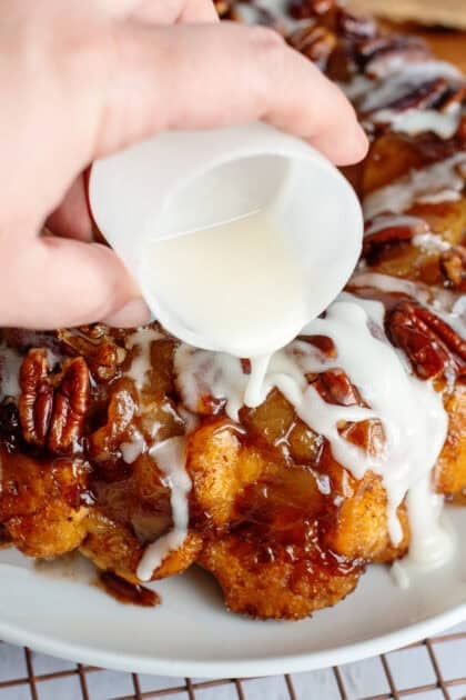 Pouring icing on apple pie cinnamon roll monkey bread.