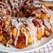 Apple pie cinnamon roll monkey bread on a plate with icing.