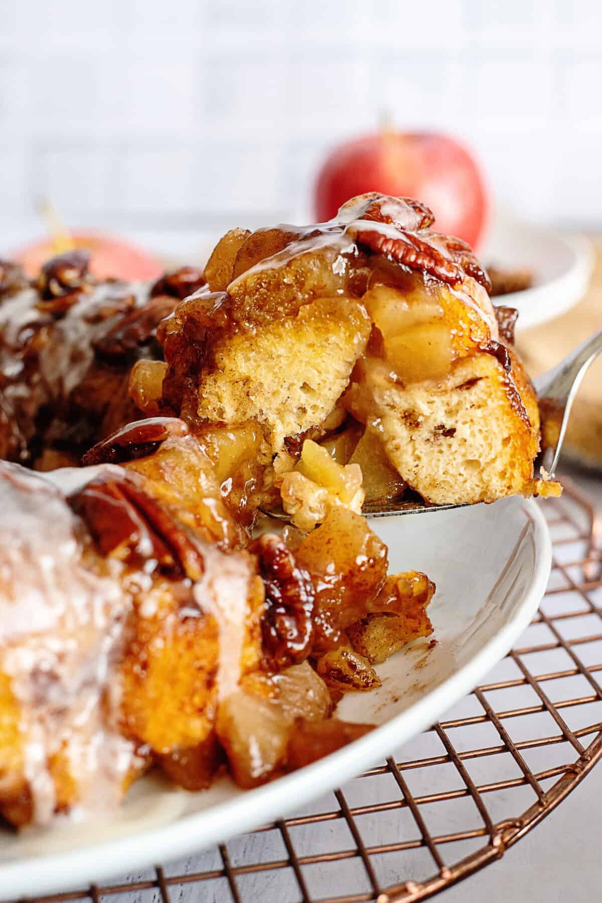 Pulling a slice of apple pie cinnamon roll monkey bread with a spatula.