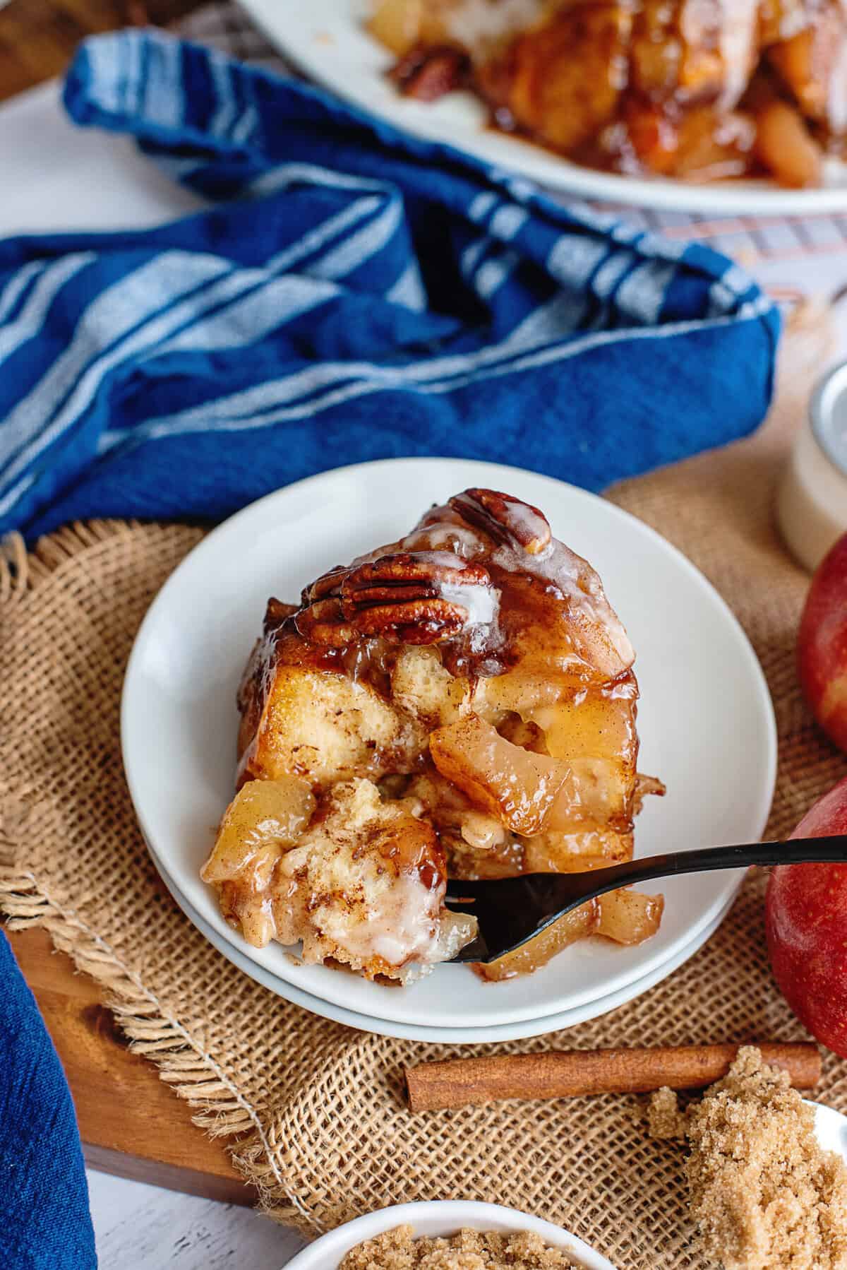 A slice of apple pie cinnamon roll monkey bread on a plate with a fork.
