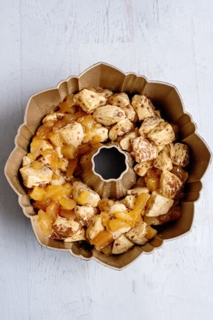 Apple pie coated cinnamon rolls in a bundt cake pan.