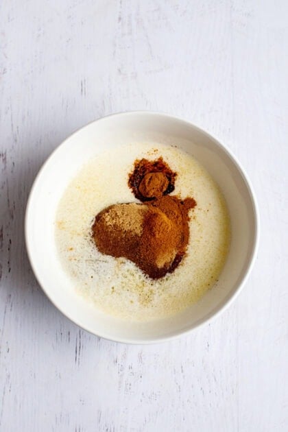 Melted butter, brown sugar, cinnamon, and vanilla in a white shallow dish.