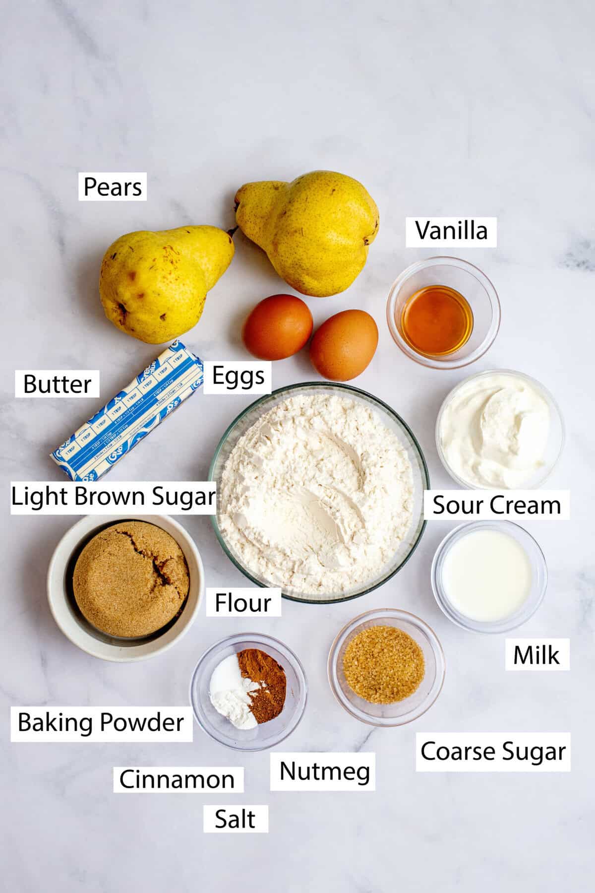 Ingredients for brown butter pear muffins featuring butter, all-purpose flour, light brown sugar, baking powder, cinnamon, salt, nutmeg, eggs, sour cream, milk, vanilla extract, pears, and turbinado sugar.