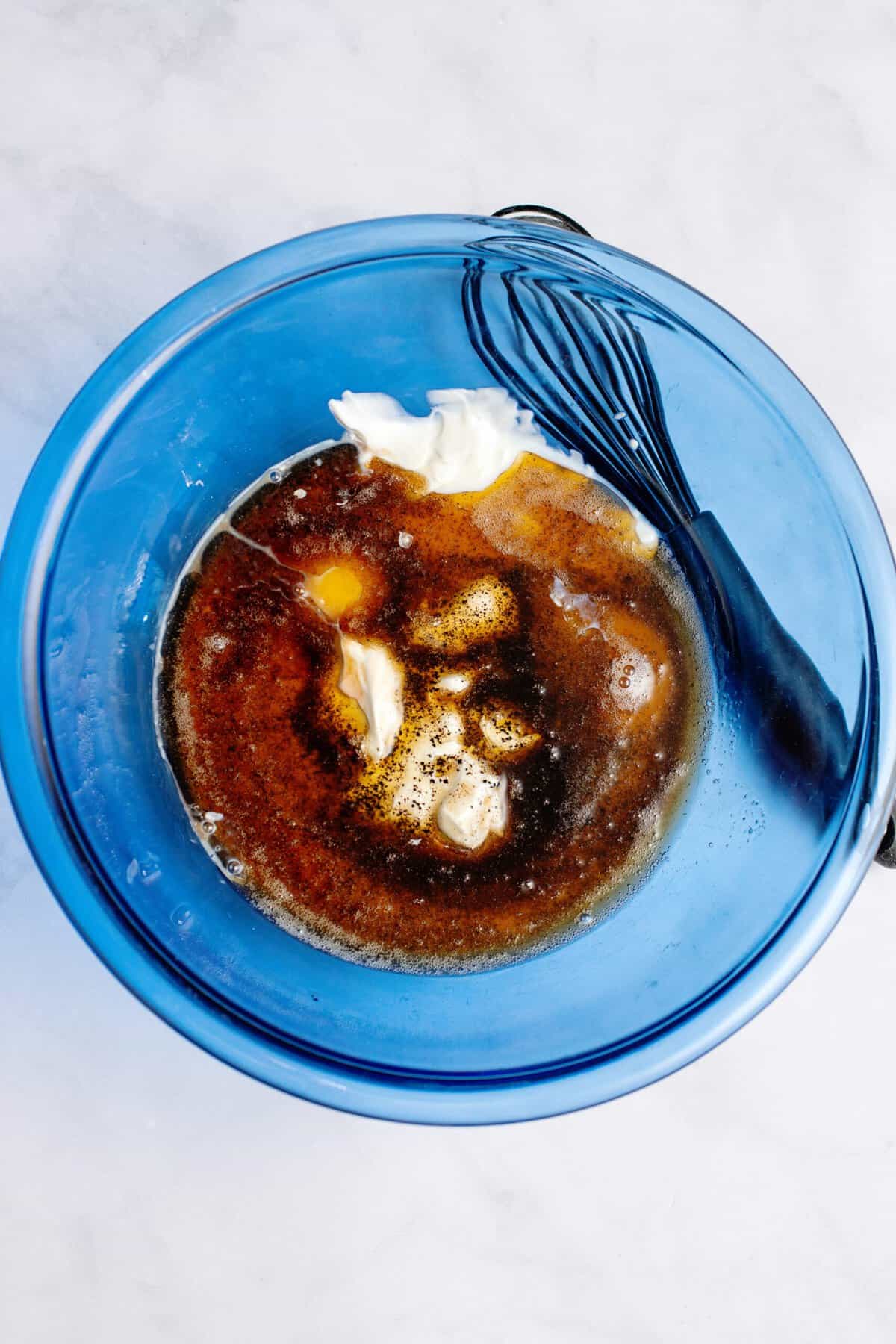 Wet ingredients in a glass blue mixing bowl.