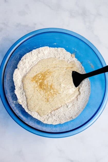 Combining wet and dry ingredients in a glass blue mixing bowl.