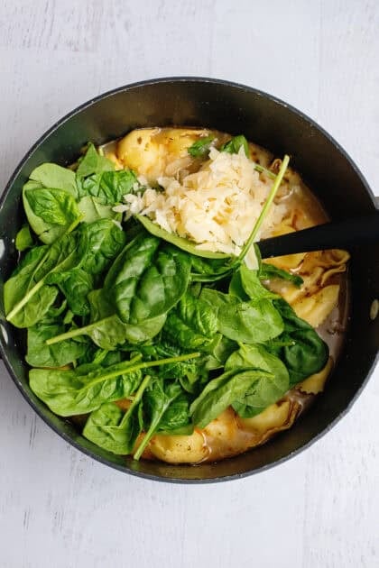 Spinach and parmesan in a pot of tortellini soup.