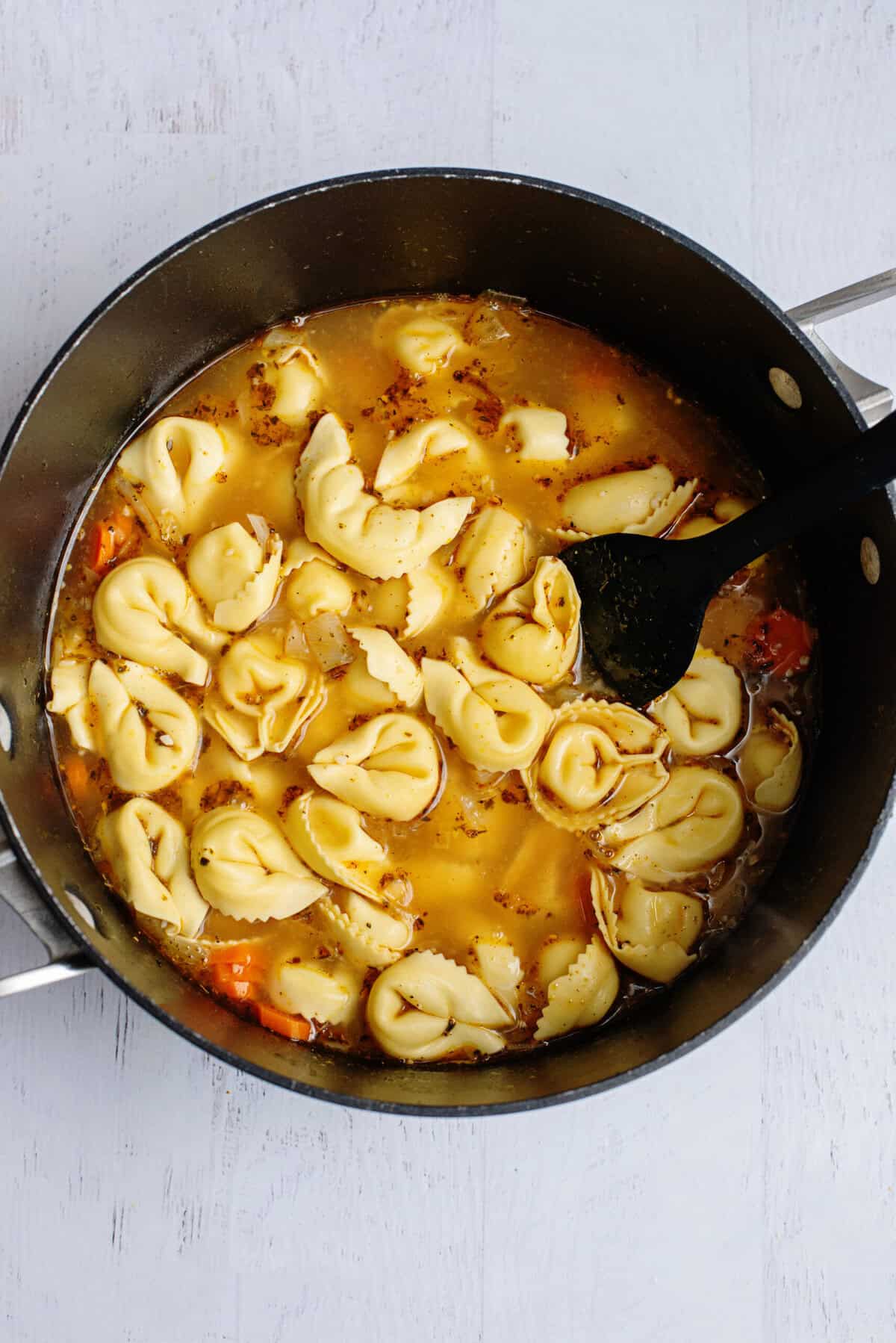Cooking tortellini in a pot of broth.
