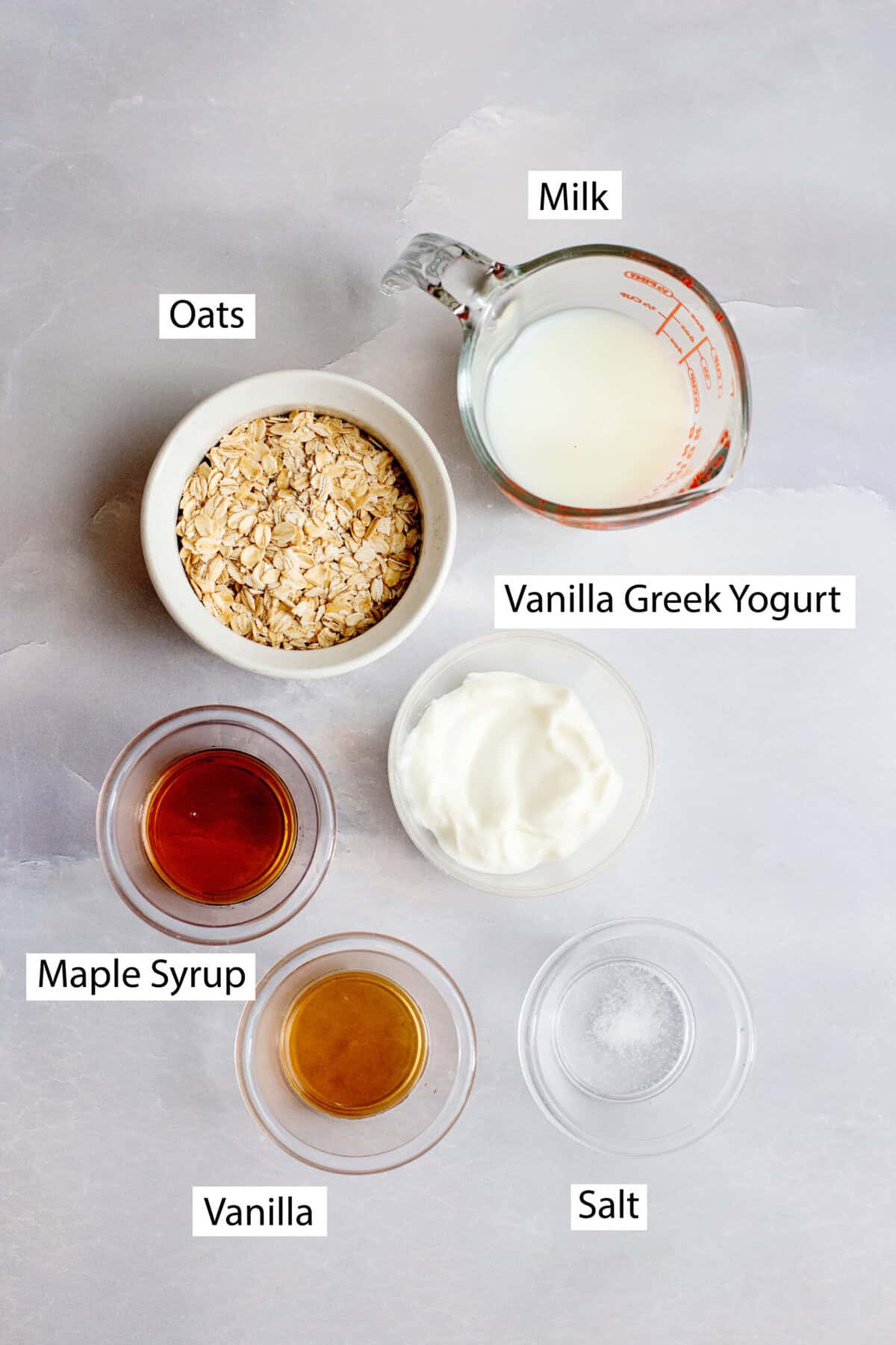 Ingredients for vanilla maple overnight oats, featuring old-fashioned rolled oats, milk, vanilla Greek yogurt, maple syrup, vanilla extract, and salt.