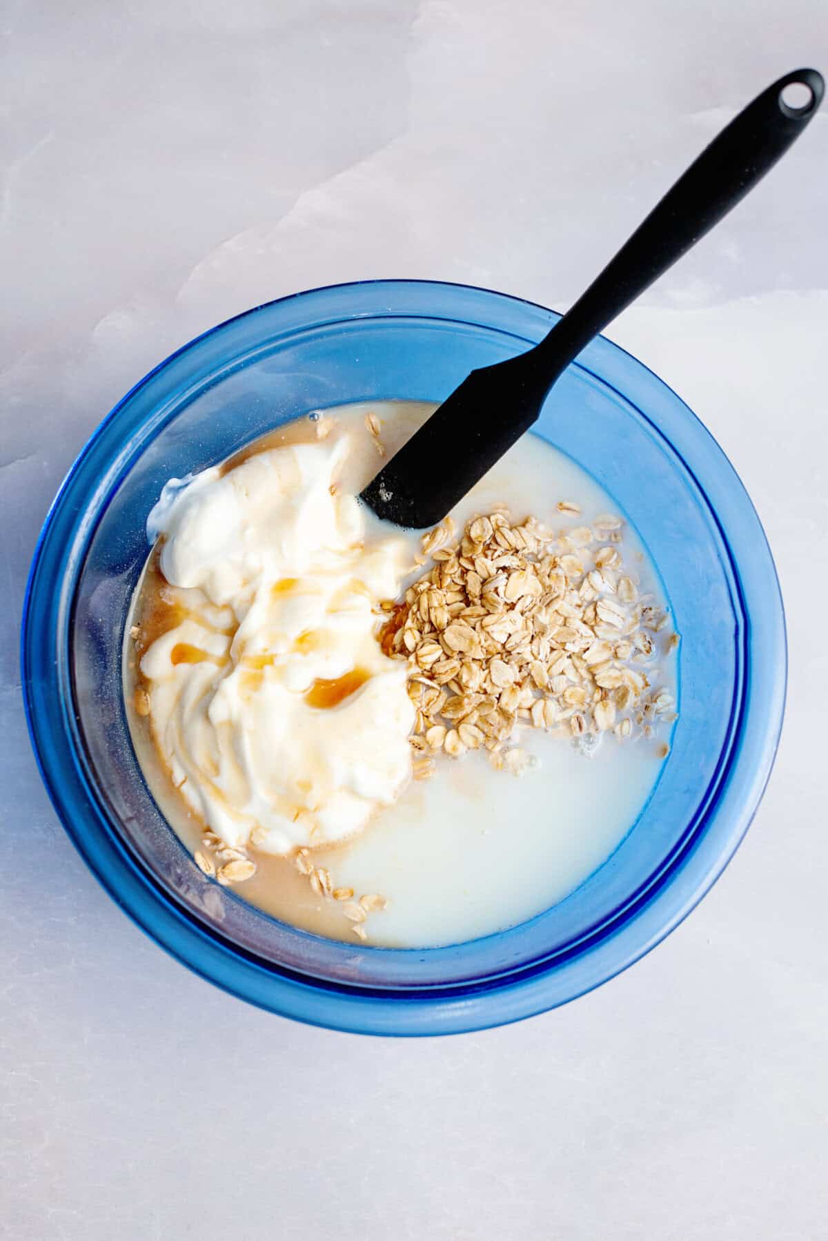 Mixture for overnight oats in a glass blue mixing bowl.