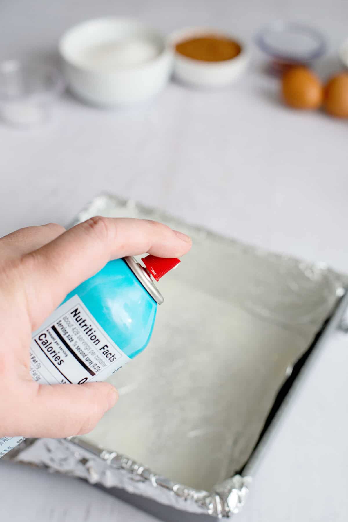 Spraying a pan with cooking spray lines with parchment paper.