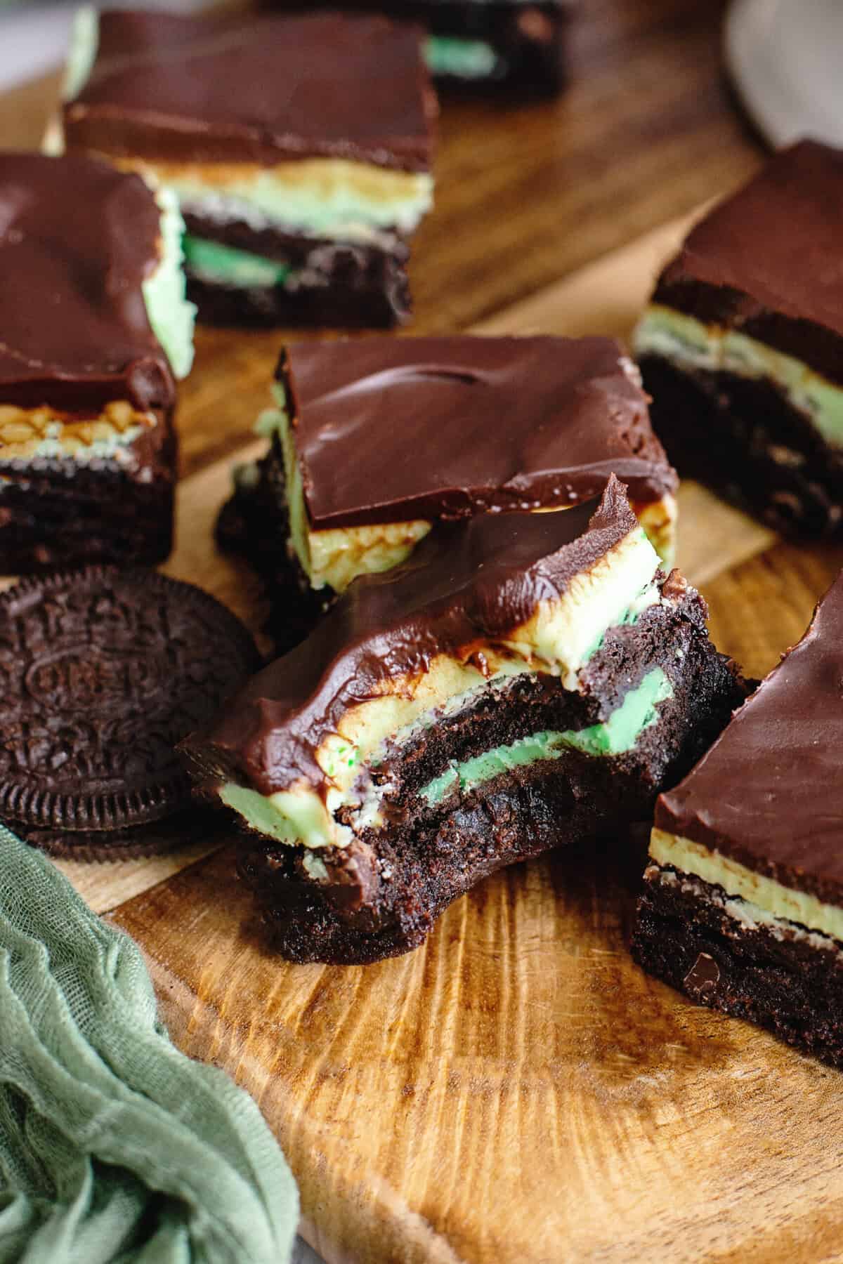 Grasshopper brownies on a wooden cutting board with one with a bite taken out of it.