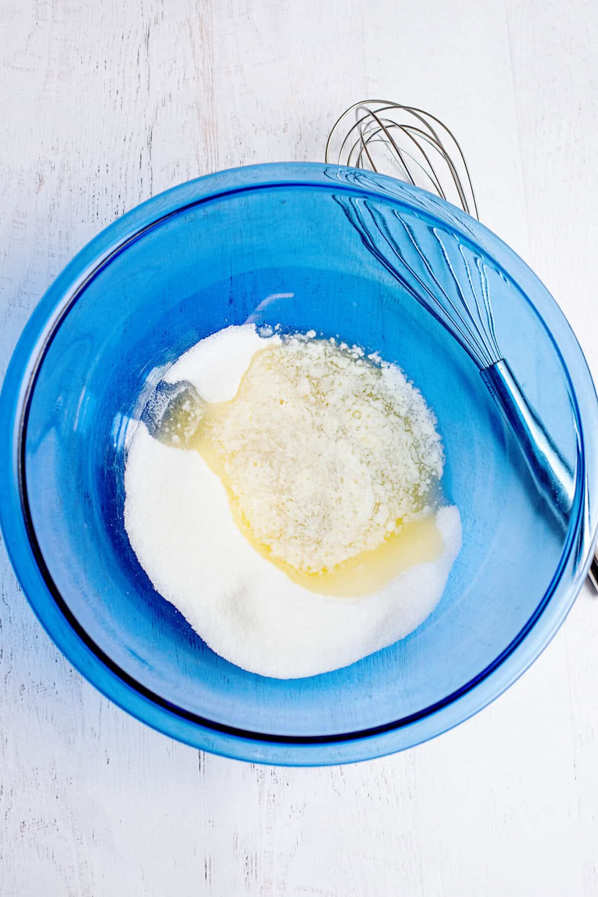 Melted butter and sugar in a glass blue mixing bowl.