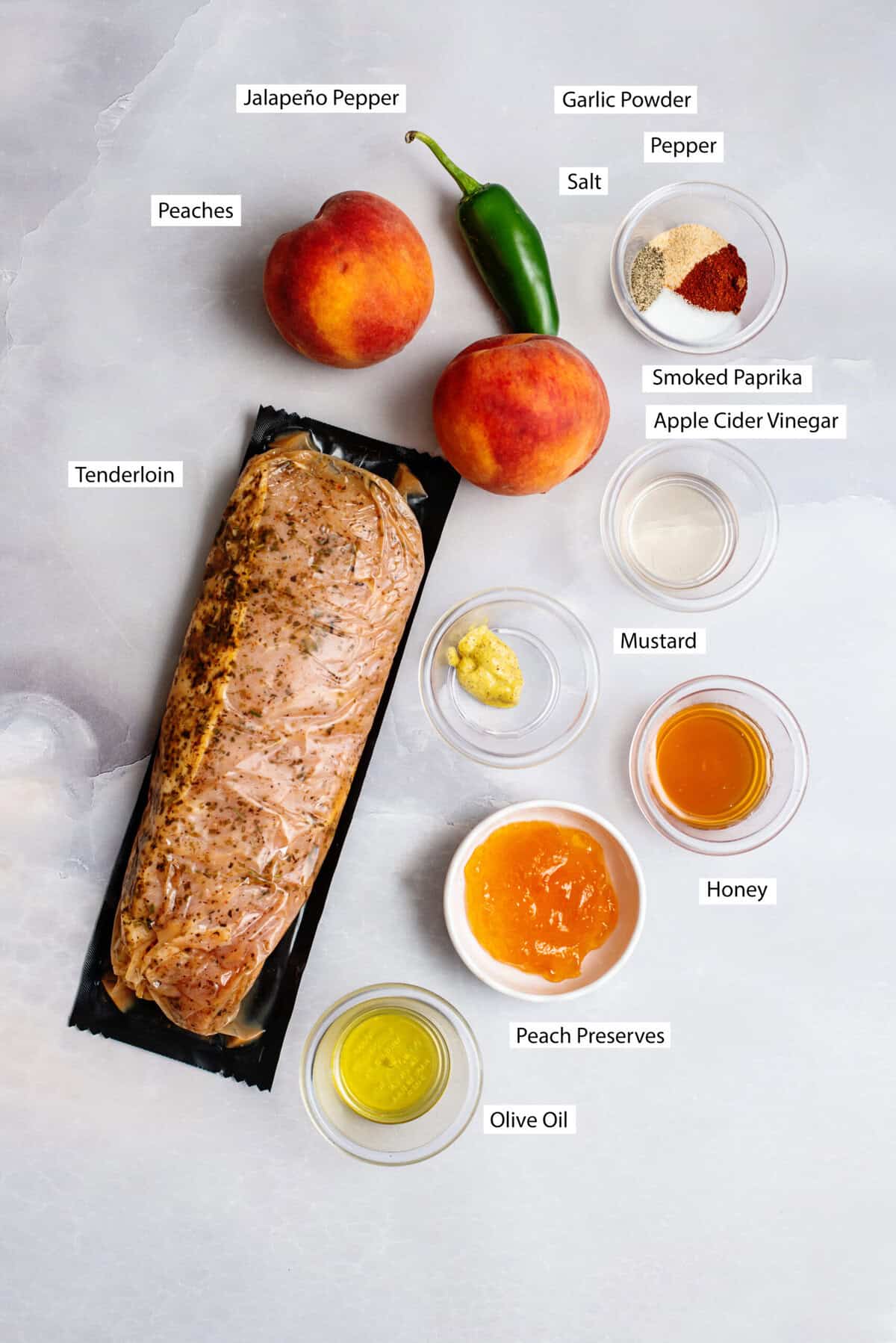 Ingredients for Grilled Peach & Jalapeño Glazed Pork Tenderloin, featuring pork tenderloin, olive oil, salt, pepper, garlic powder, paprika, peaches, jalapeno, peach preserves, honey, apple cider vinegar, and Dijon.