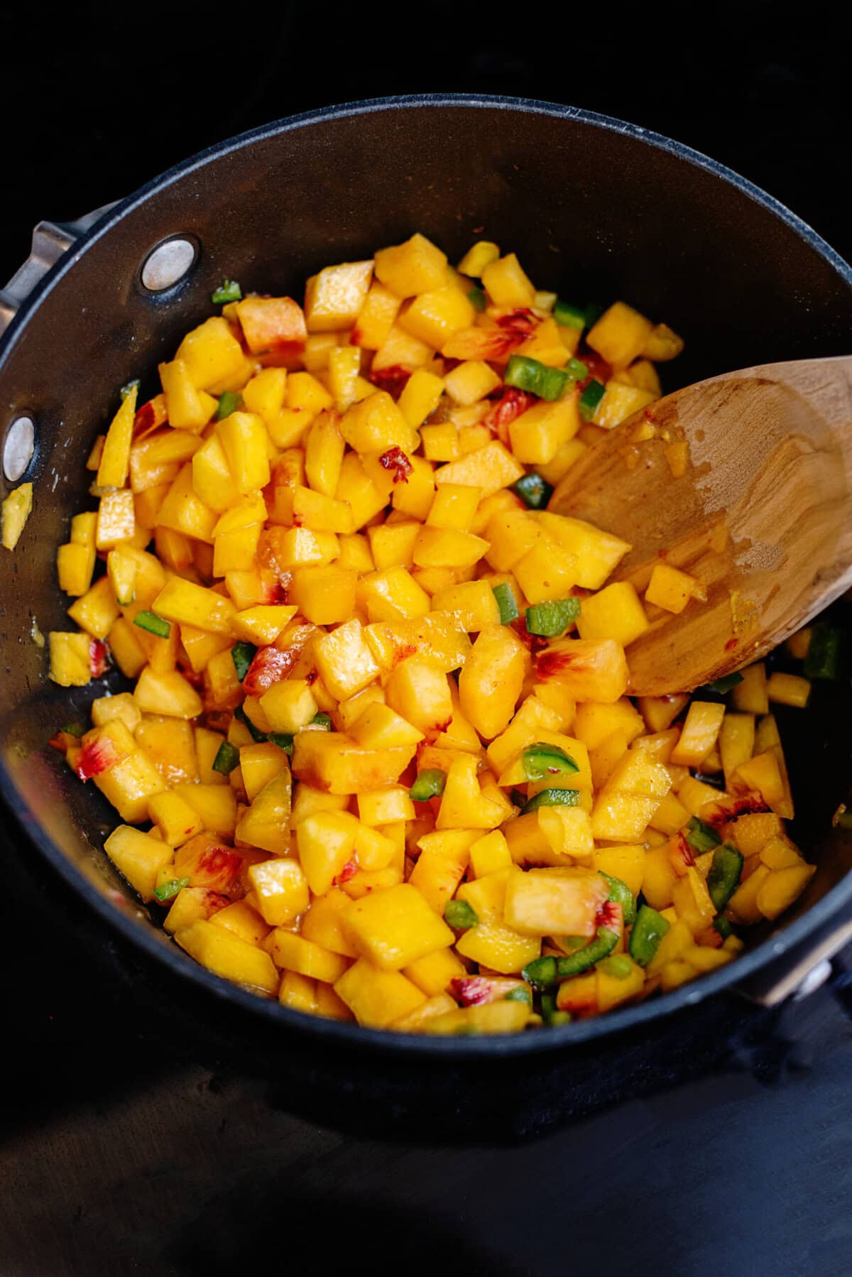 Peaches, jalapeño, peach preserves, honey, apple cider vinegar, Dijon mustard, and salt cooking in a skillet.