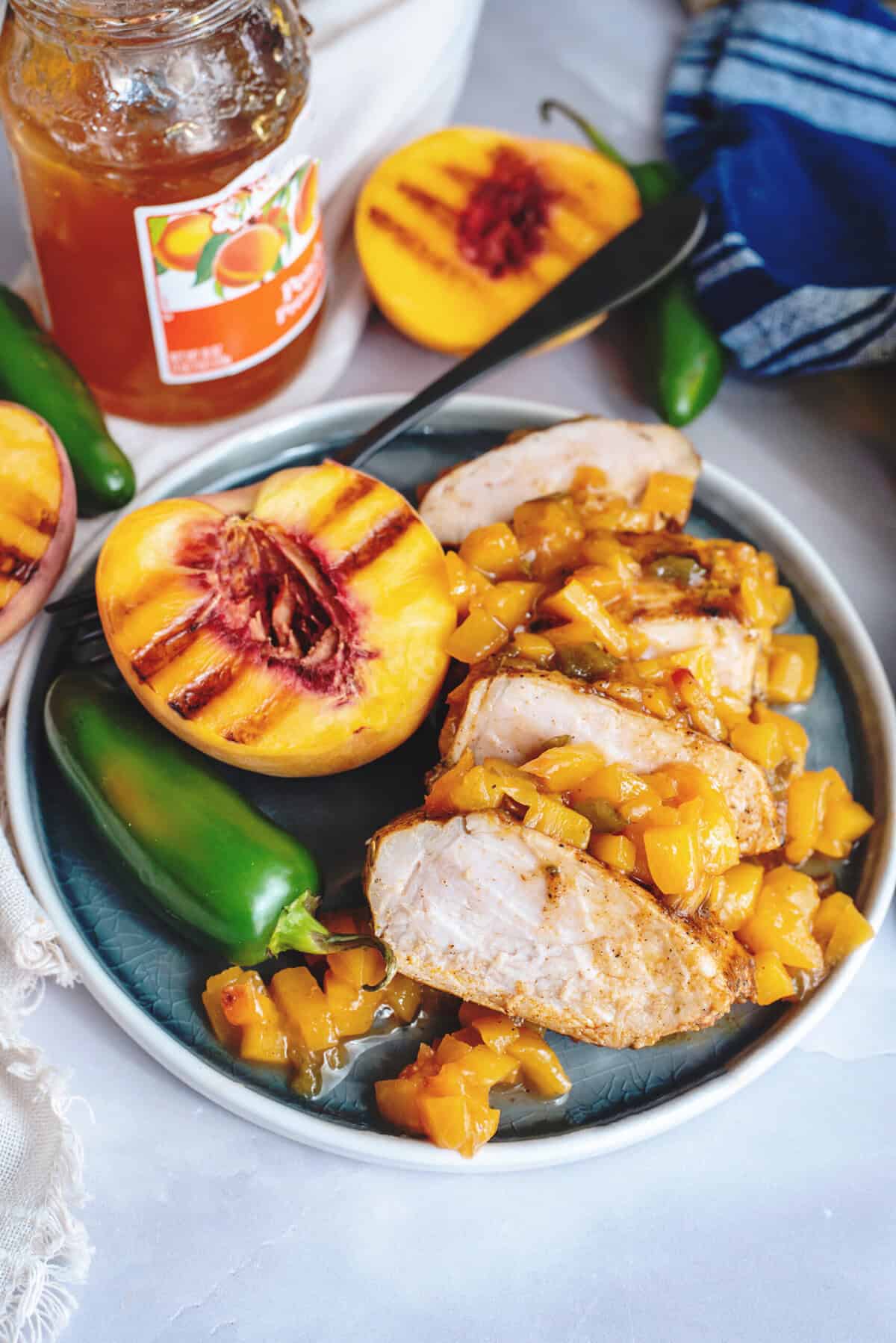 Grilled peach jalapeno glazed pork tenderloin sliced on a plate.