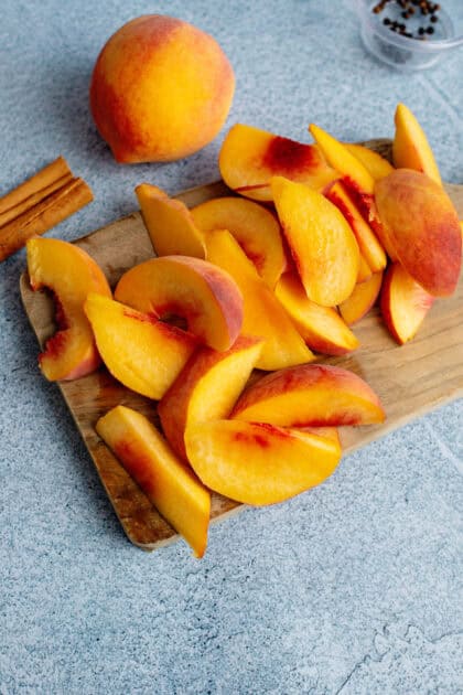 Sliced peaches on a wooden cutting board.