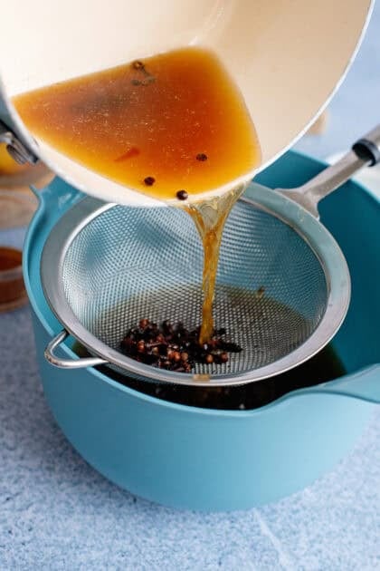 Pouring hot brine through a strainer.