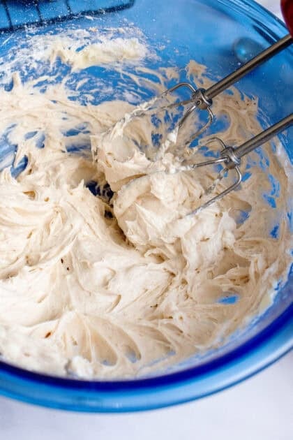 Beating cream cheese filling in a mixing bowl.