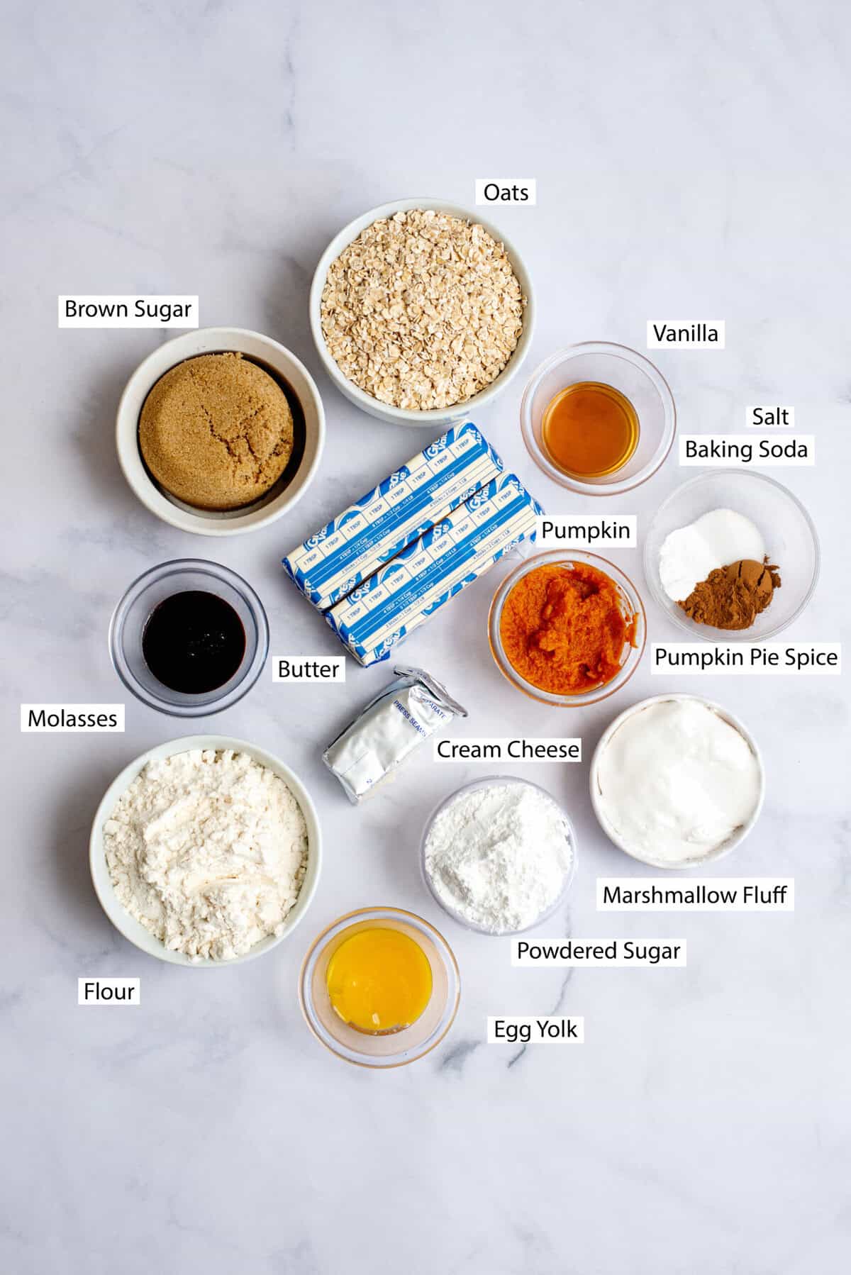 Ingredients for pumpkin oatmeal cream pies, featuring butter, brown sugar, pumpkin puree, egg yolk, vanilla extract, molasses, all-purpose flour, baking soda, pumpkin pie spice, salt, quick-cooking oats, cream cheese, marshmallow fluff, and powdered sugar.