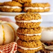 Pumpkin spice oatmeal cream pies stacked on each other next to a pumpkin.