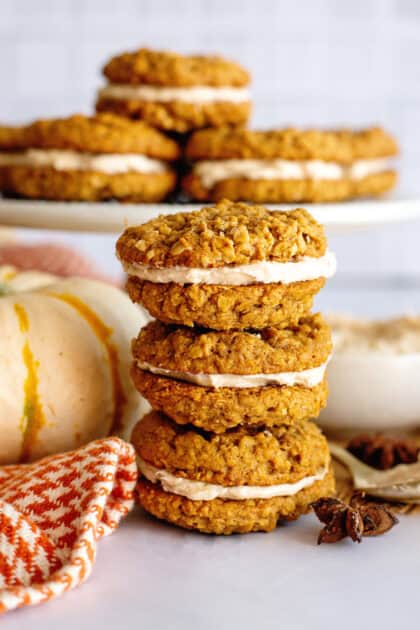 Pumpkin spice oatmeal cream pies stacked on each other next to a pumpkin.