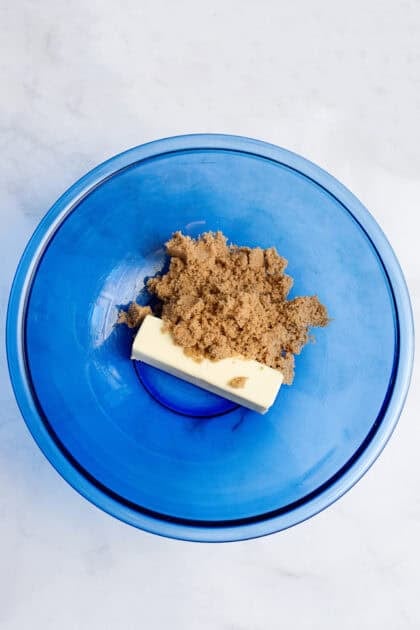 Butter and brown sugar in a glass blue mixing bowl.