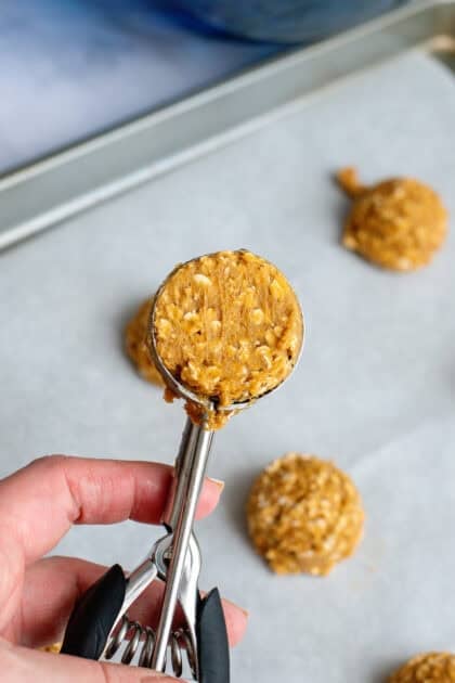A cookie scoop with pumpkin oatmeal cookie dough.