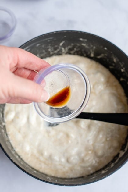 Pouring vanilla extract in a pot of melted marshmallows.