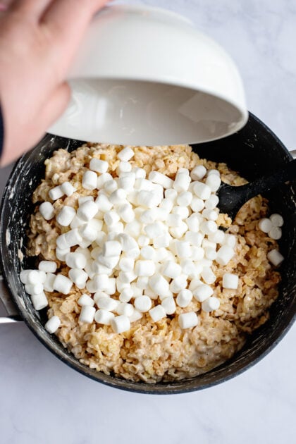 Layering on mini marshmallows to a large pot of Rice Krispies.