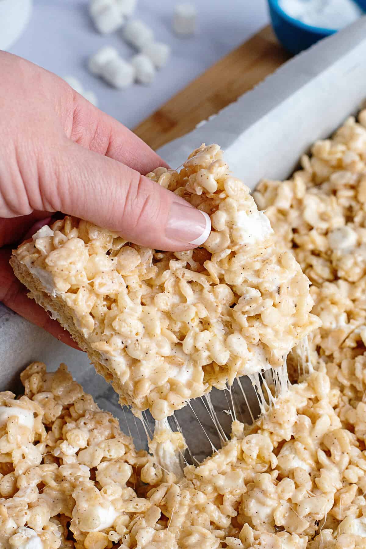 A hand grabbing a square of Rice Krispie treats.