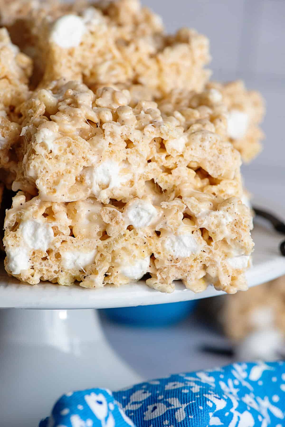 Rice Krispie treats stacked on each other on a cake stand.