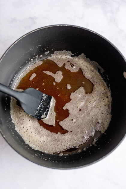 Brown butter in a large pot with a black spatula.