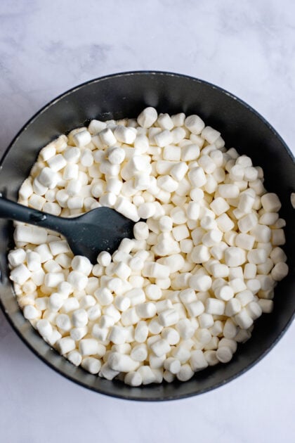 Mini marshmallows in a bowl with a black spatula.